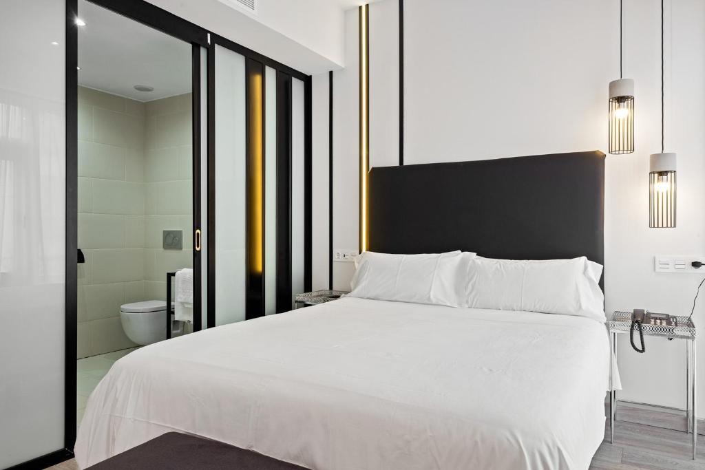 a bedroom with a large white bed and a bathroom at Urban Anaga Hotel in Santa Cruz de Tenerife