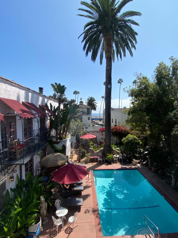 a swimming pool next to a hotel with a palm tree at Villa Rosa Inn in Santa Barbara
