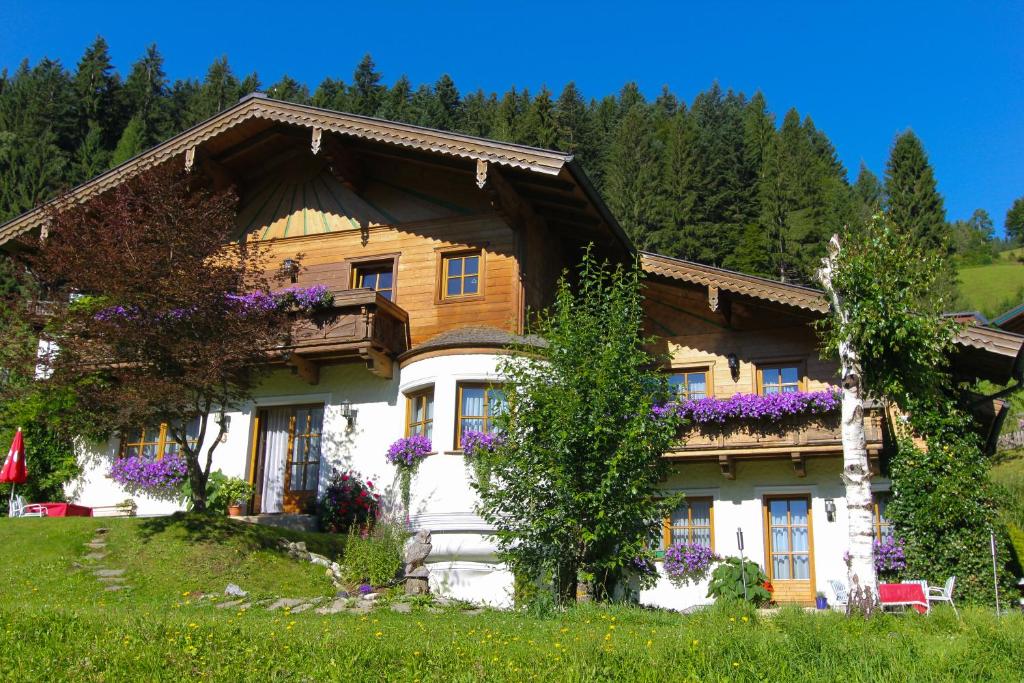 Una casa con flores púrpuras a un lado. en Landhaus Gaspar, en Wagrain