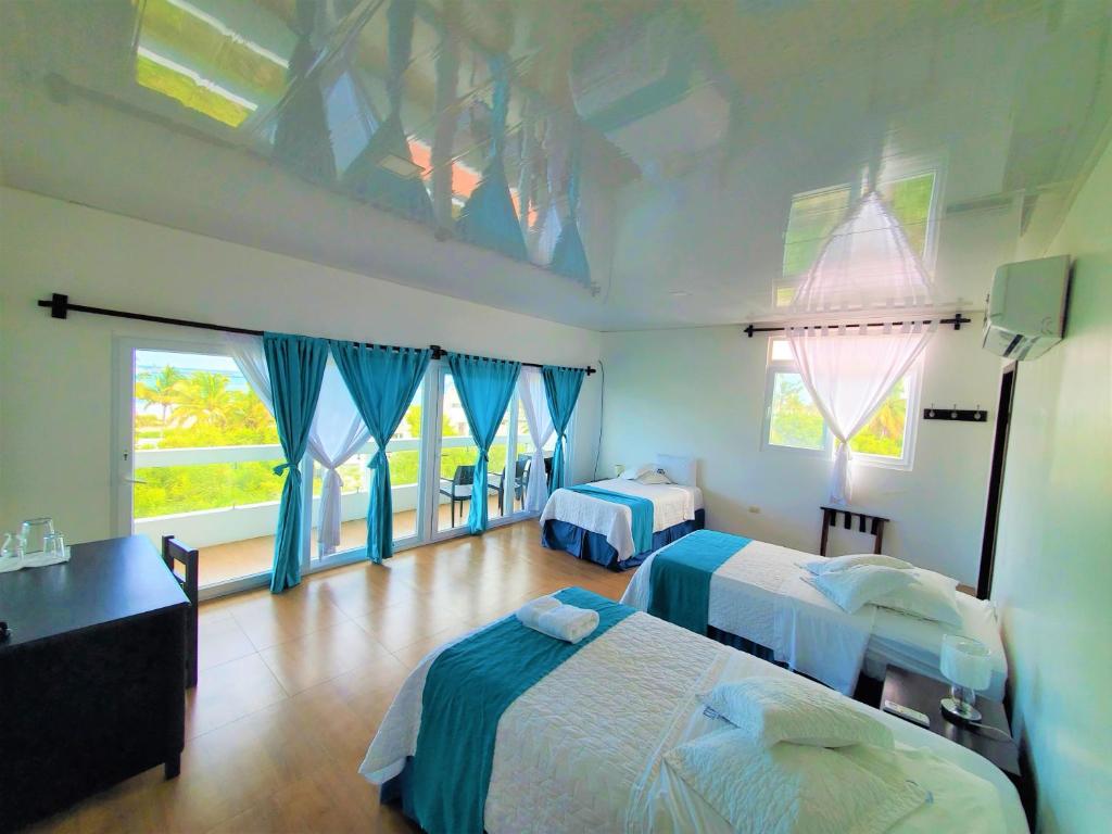 um quarto com 2 camas e cortinas azuis em Hotel Cally em Puerto Villamil