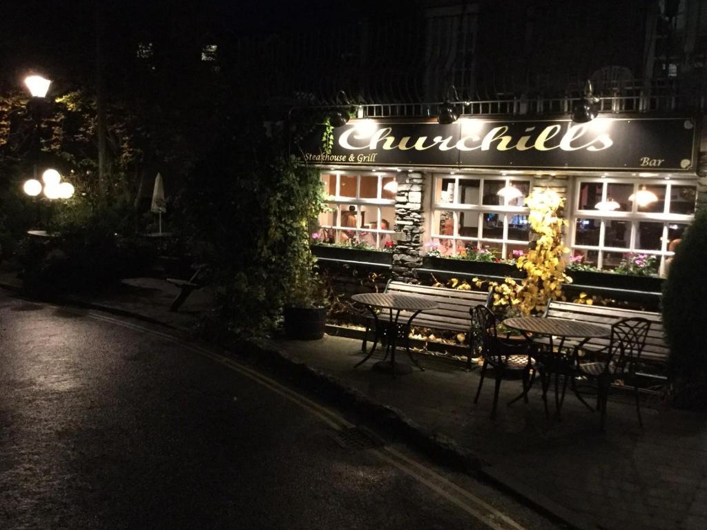 a restaurant with tables and chairs at night at Churchills Inn & Rooms in Bowness-on-Windermere
