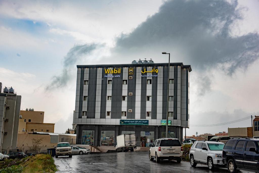 un edificio de hotel con coches aparcados en un aparcamiento en وابل للوحدات السكنية, en Abha