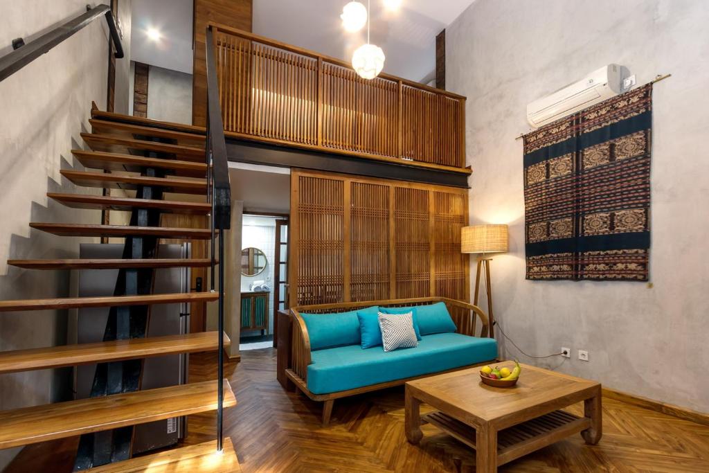 a living room with a blue couch and stairs at Ruang Tekuni in Legian