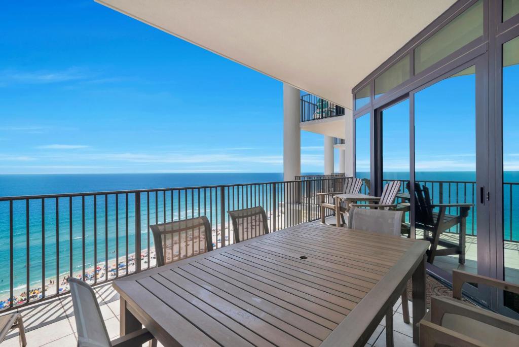 a balcony with a wooden table and chairs and the ocean at The Oasis at Orange Beach (formerly Phoenix West II) in Orange Beach