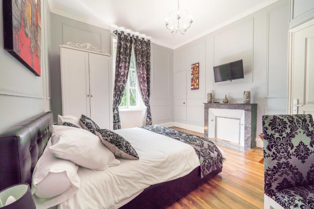 een slaapkamer met een bed met kussens en een open haard bij Château de Baillant - Futuroscope in Vendeuvre-du-Poitou