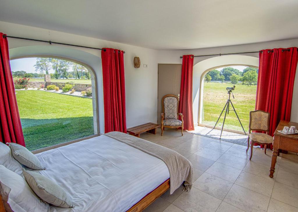 a bedroom with a bed and a large window at Domaine de kerbillec in Theix