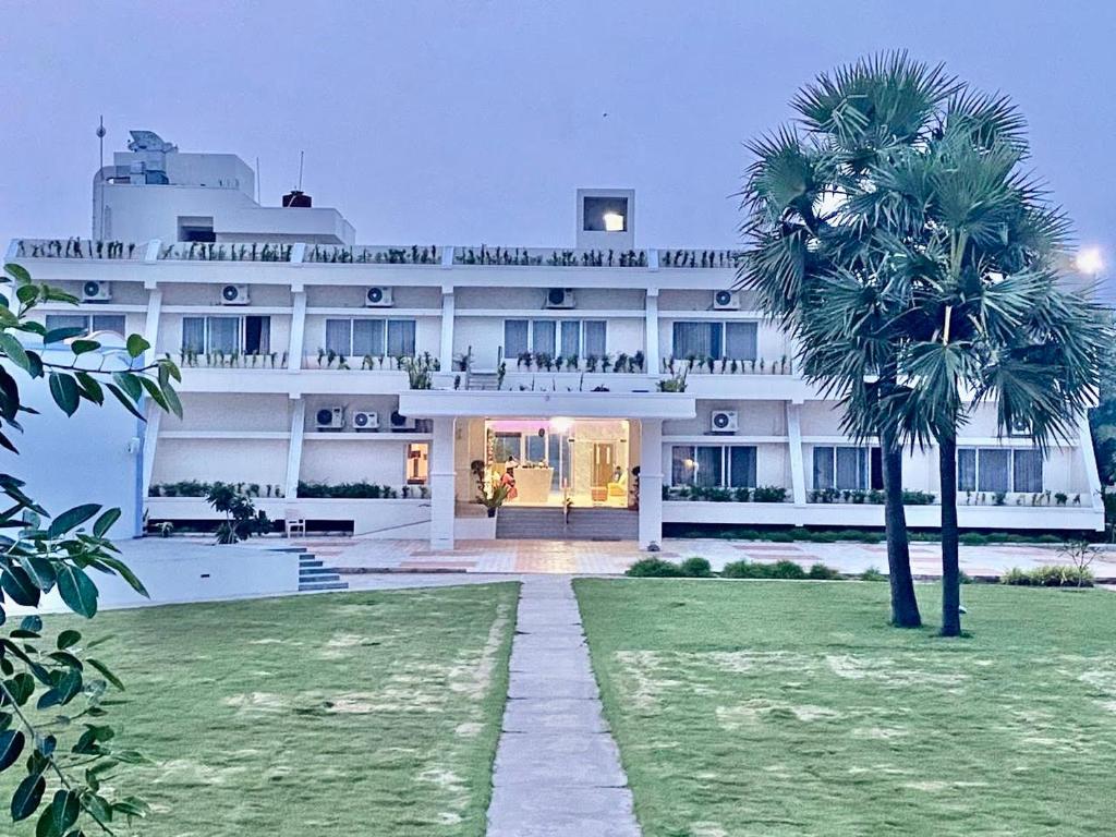 ein großes weißes Gebäude mit einer Palme davor in der Unterkunft Riviera Beach Resort in Chīrāla
