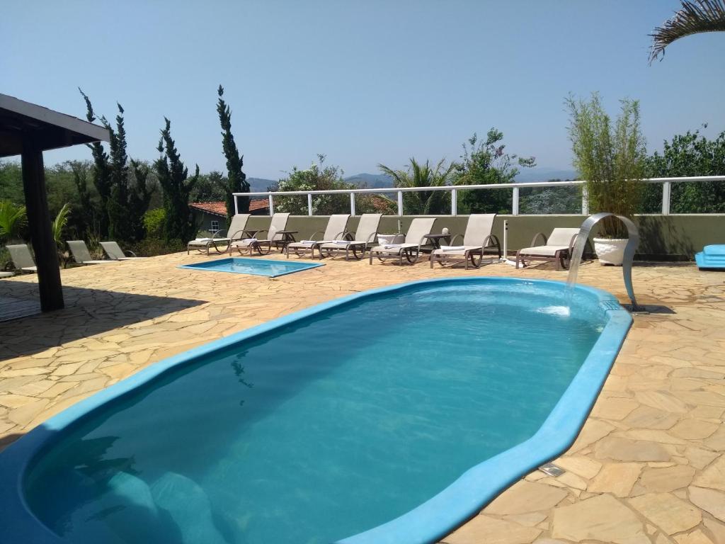 a large swimming pool with chairs and a patio at Ladiv'ttá Hotel in Atibaia