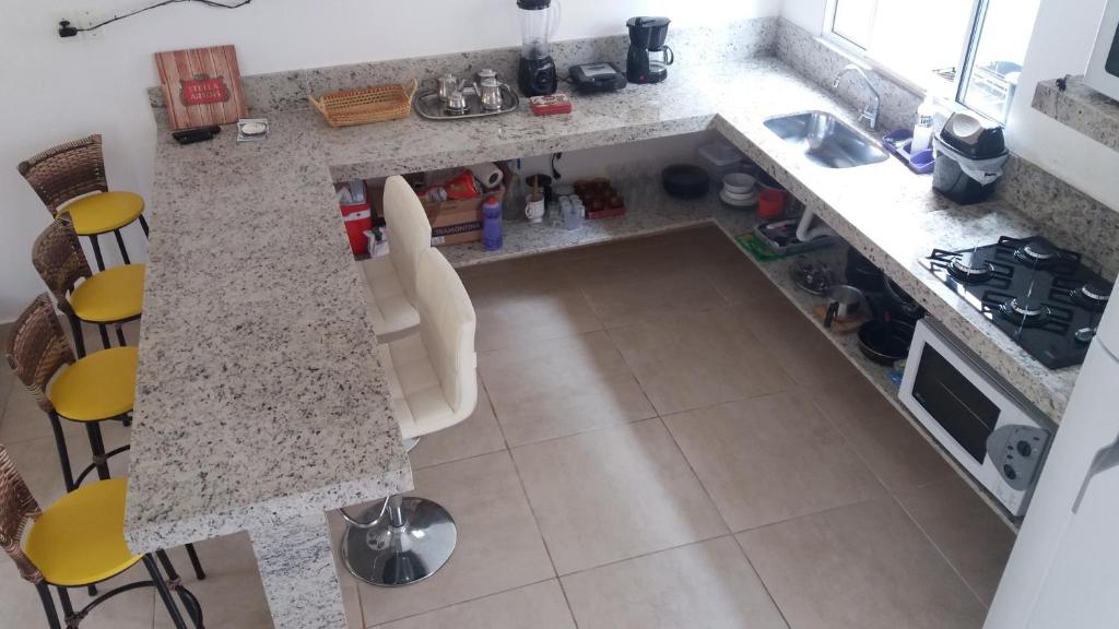 an aerial view of a kitchen with a counter and chairs at Descanso e aconchego massaguacu in Caraguatatuba