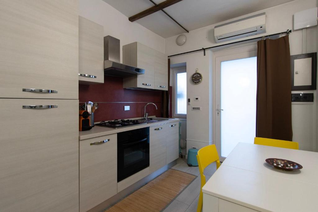una cocina con armarios blancos y una mesa con sillas amarillas en Santa Chiara, en Turín