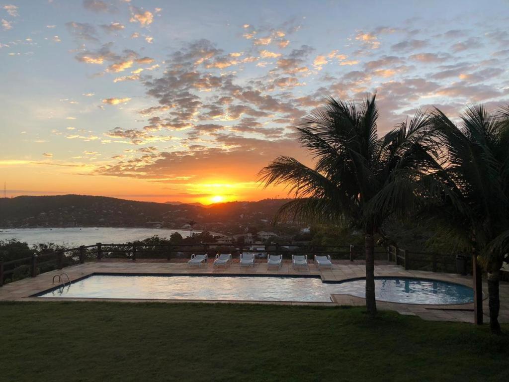 um pôr-do-sol sobre uma piscina num resort em Suite Independente Por do Sol Ferradura em Búzios