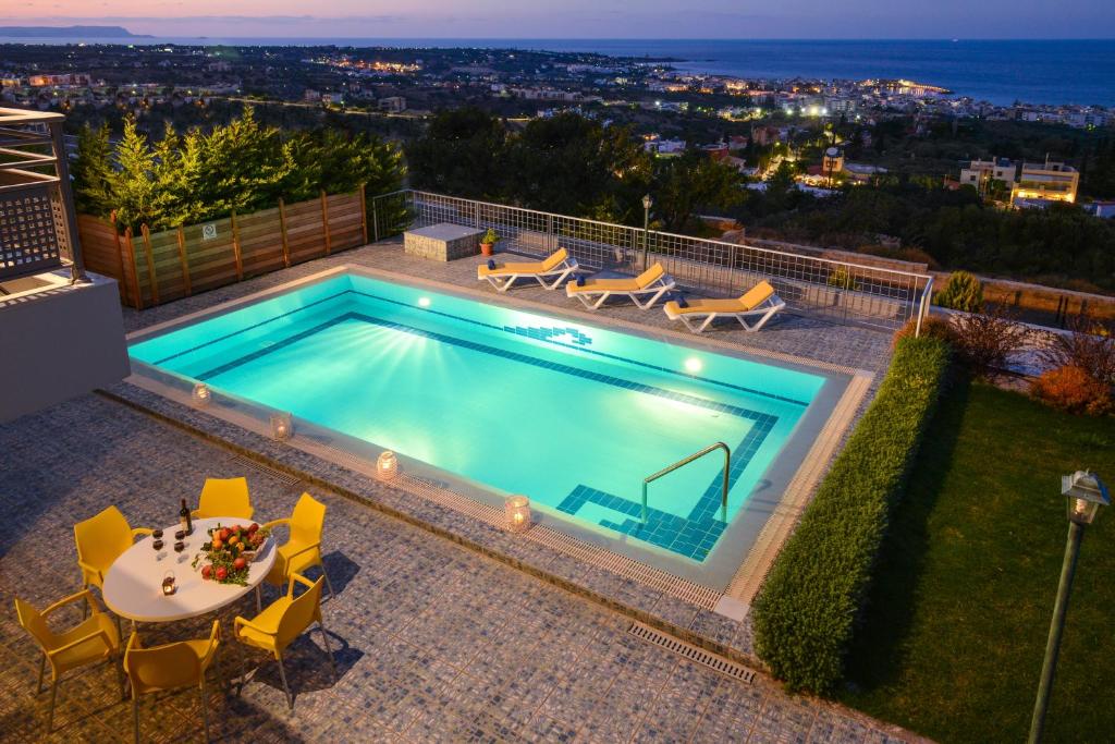 a swimming pool with a table and chairs at Danae Villas in Hersonissos