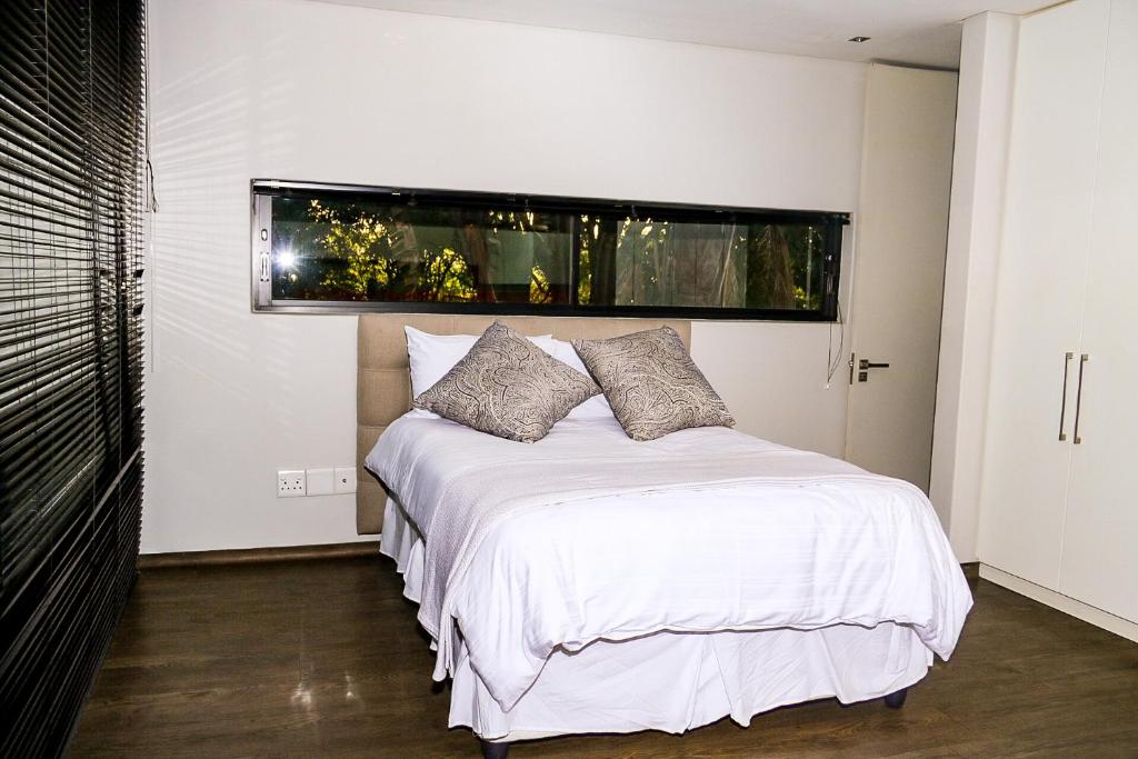 a bedroom with a white bed with a window at Ten On Lane in Polokwane