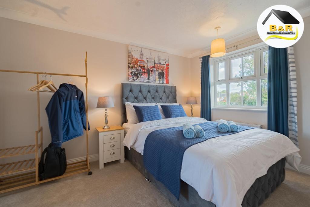 ein Schlafzimmer mit einem großen Bett mit blauer Bettwäsche und blauen Kissen in der Unterkunft Javelin House- B and R Serviced Accommodation Amesbury, 3 Bed Detached House with Free Parking, Super Fast Wi-Fi and 4K Smart TV in Amesbury