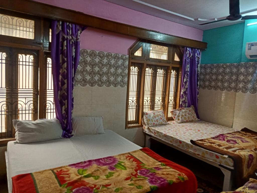 two beds in a room with purple walls and windows at Kashi Annapurna Guest House in Varanasi