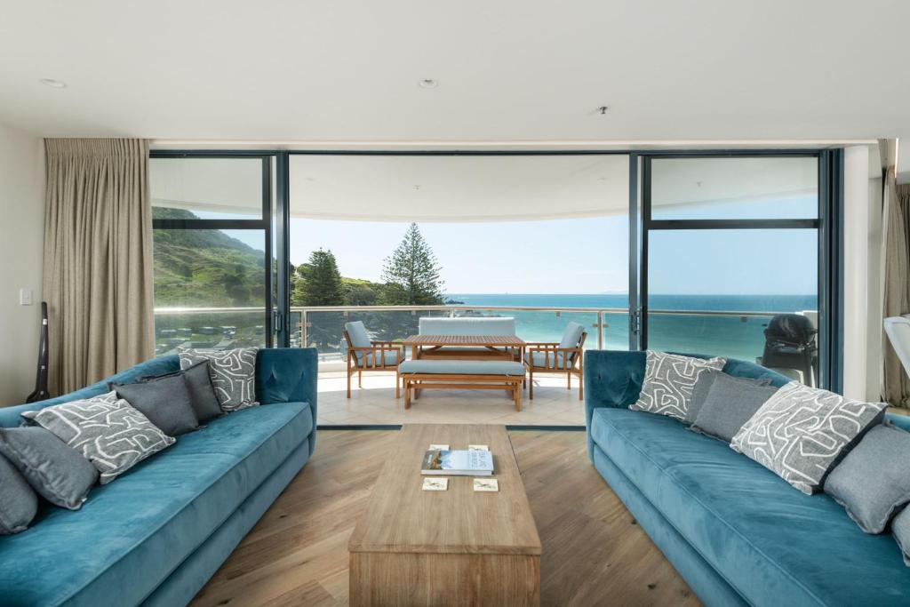 a living room with a blue couch and a table at Oceanside Haven Resort with Luxury Sea Views in Mount Maunganui