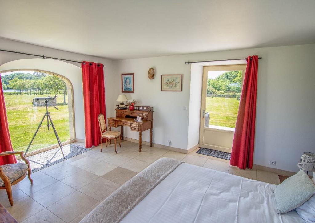 a bedroom with a bed and a desk and a window at Domaine de kerbillec in Theix