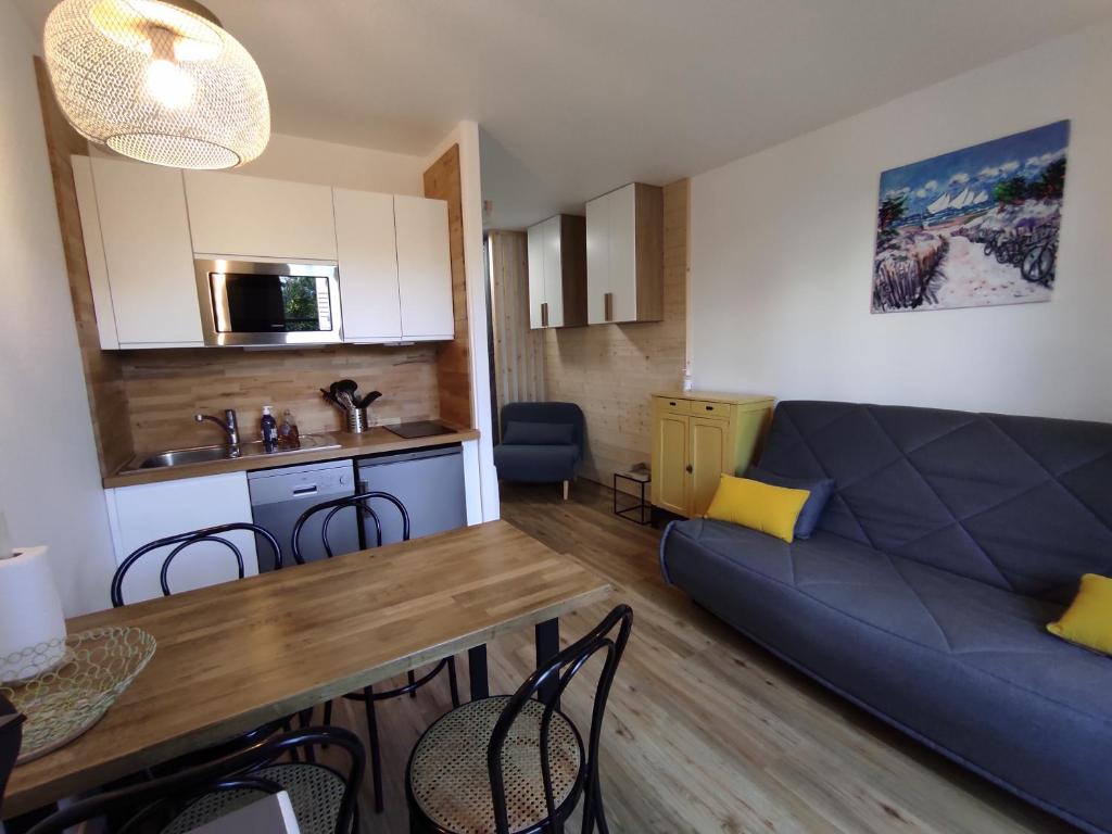 a living room with a blue couch and a kitchen at Studio avec terrasse et parking 200m plage et commerces in La Couarde-sur-Mer