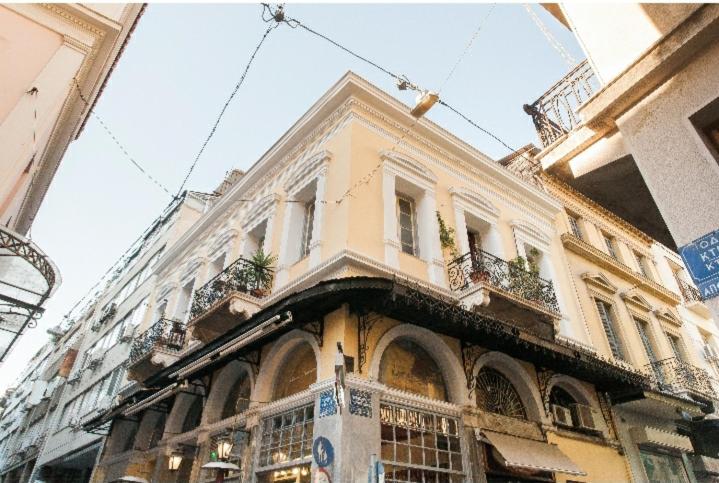 un grand bâtiment jaune avec des fenêtres et des plantes. dans l'établissement The monumental house, à Athènes