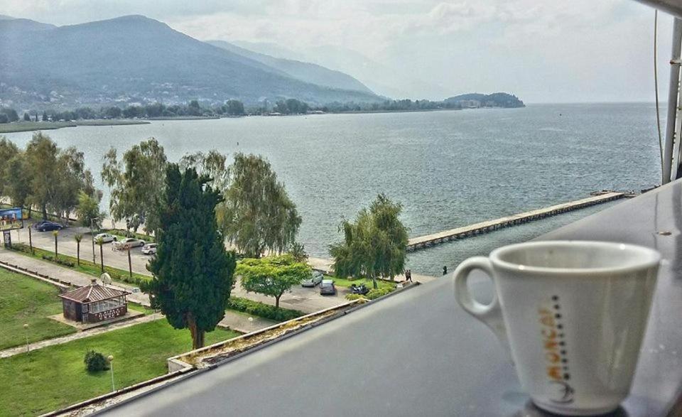 una taza de café en el alféizar de la ventana con vistas al agua en Fibos Studios, en Ohrid