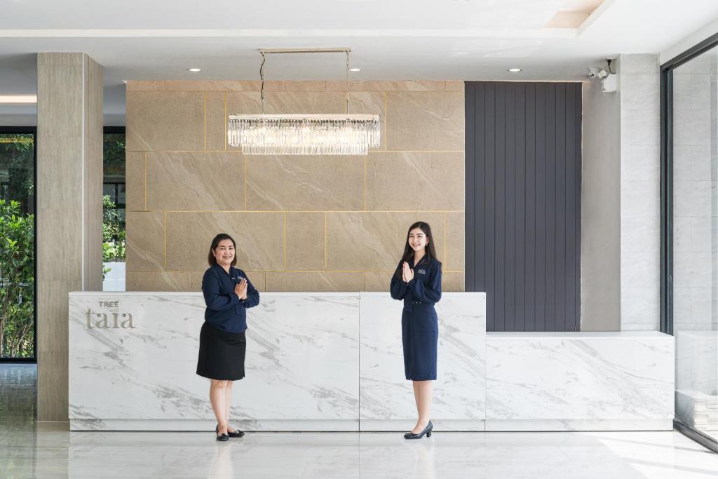 two women standing in a lobby talking on cell phones at Tree Tara hotel in Lampang