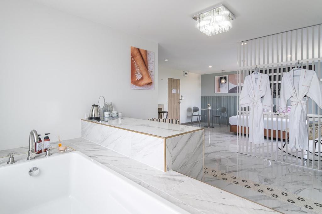 a white bathroom with a tub and a sink at Tree Tara hotel in Lampang