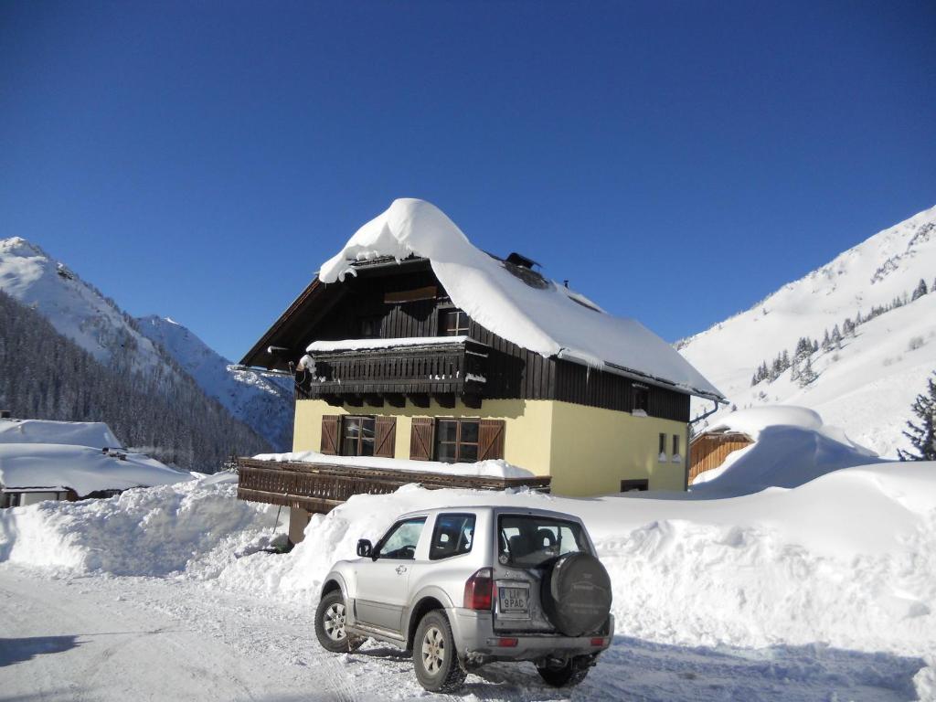 un pequeño coche aparcado frente a una casa cubierta de nieve en Haus Andrea, en Planneralm