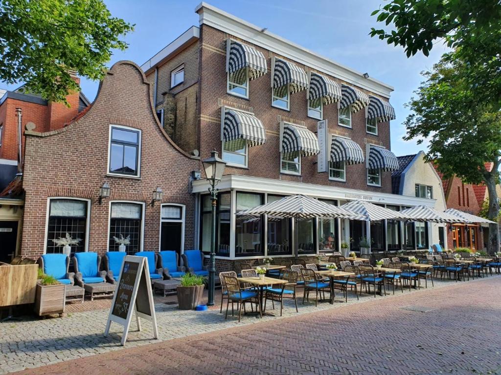un edificio con mesas y sillas delante de él en Badhotel Bruin en Oost-Vlieland