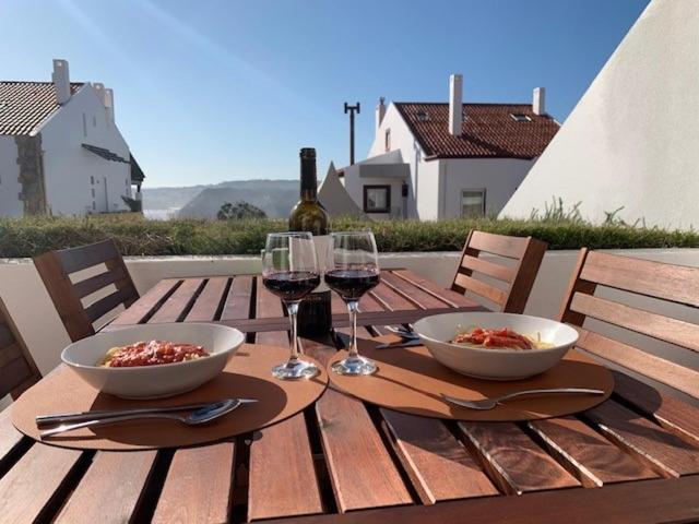 a wooden table with two bowls and glasses of wine at Casa S & S in São Martinho do Porto