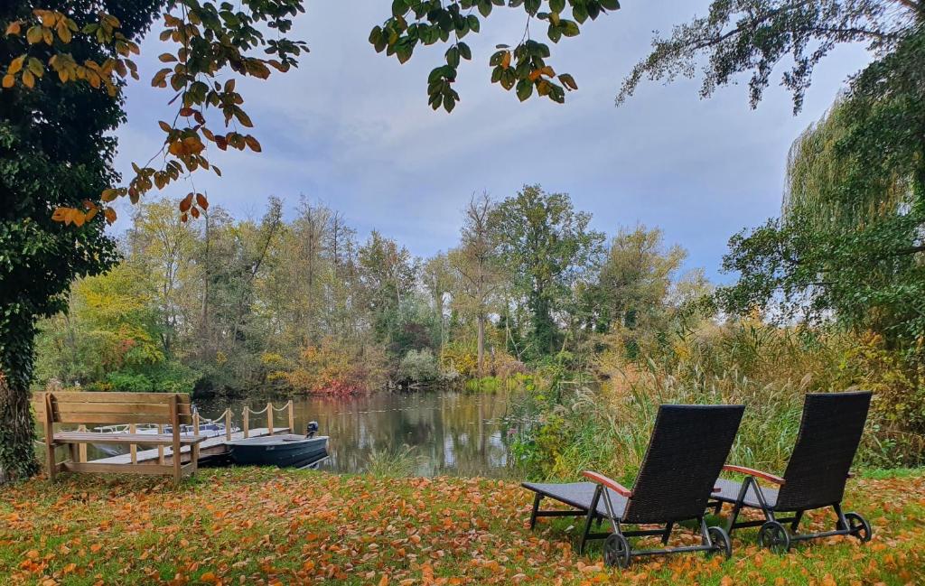 dos sillas sentadas junto a un lago con un barco en Ferienwohnung Havelblick, en Ketzin