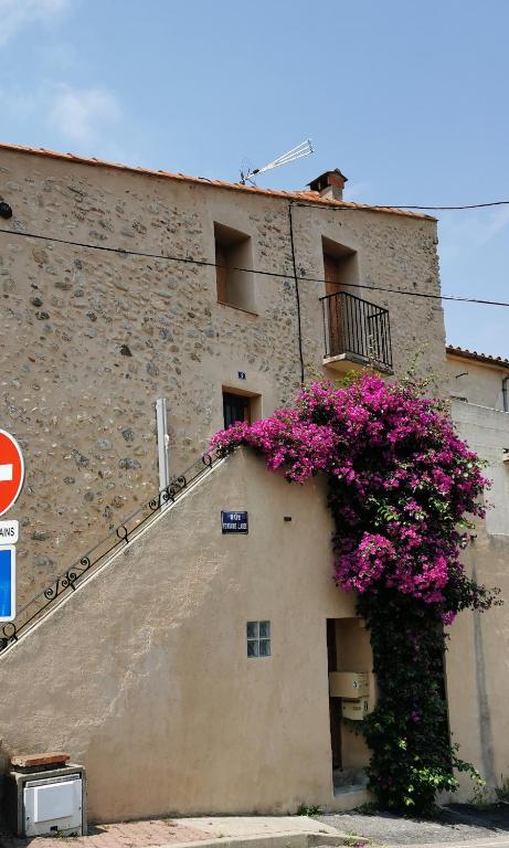 a building with pink flowers on the side of it at Appartement duplex in Le Boulou
