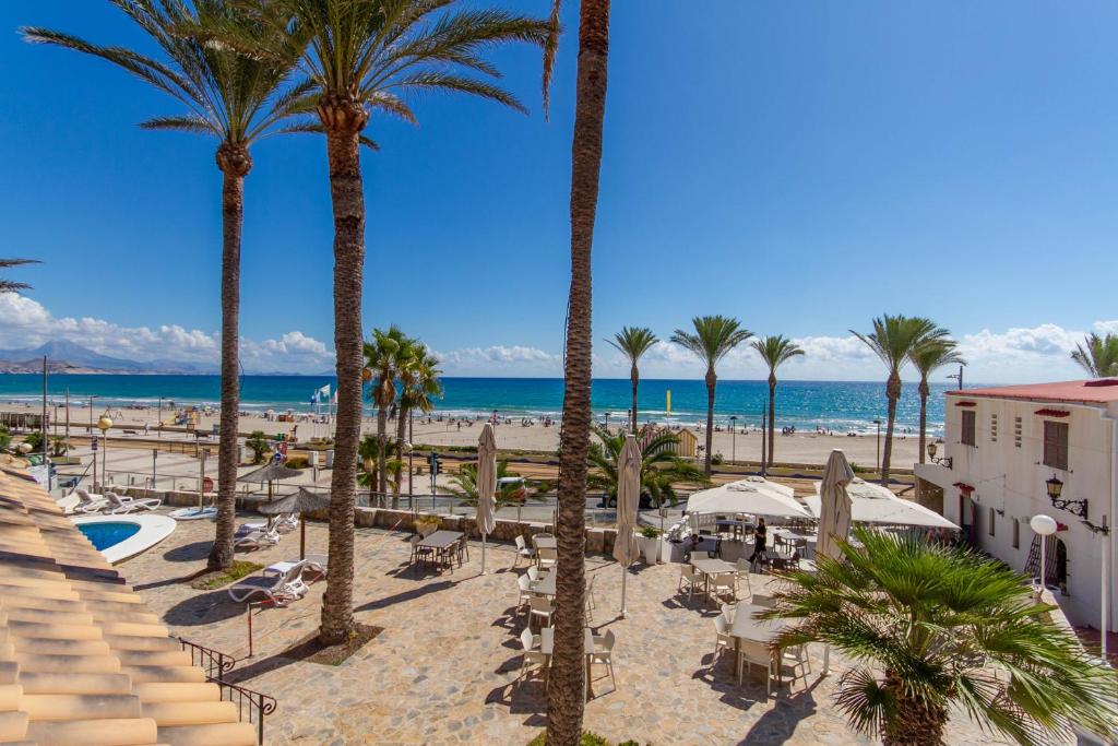 een uitzicht op een strand met palmbomen en de oceaan bij Hostal San Juan in El Campello