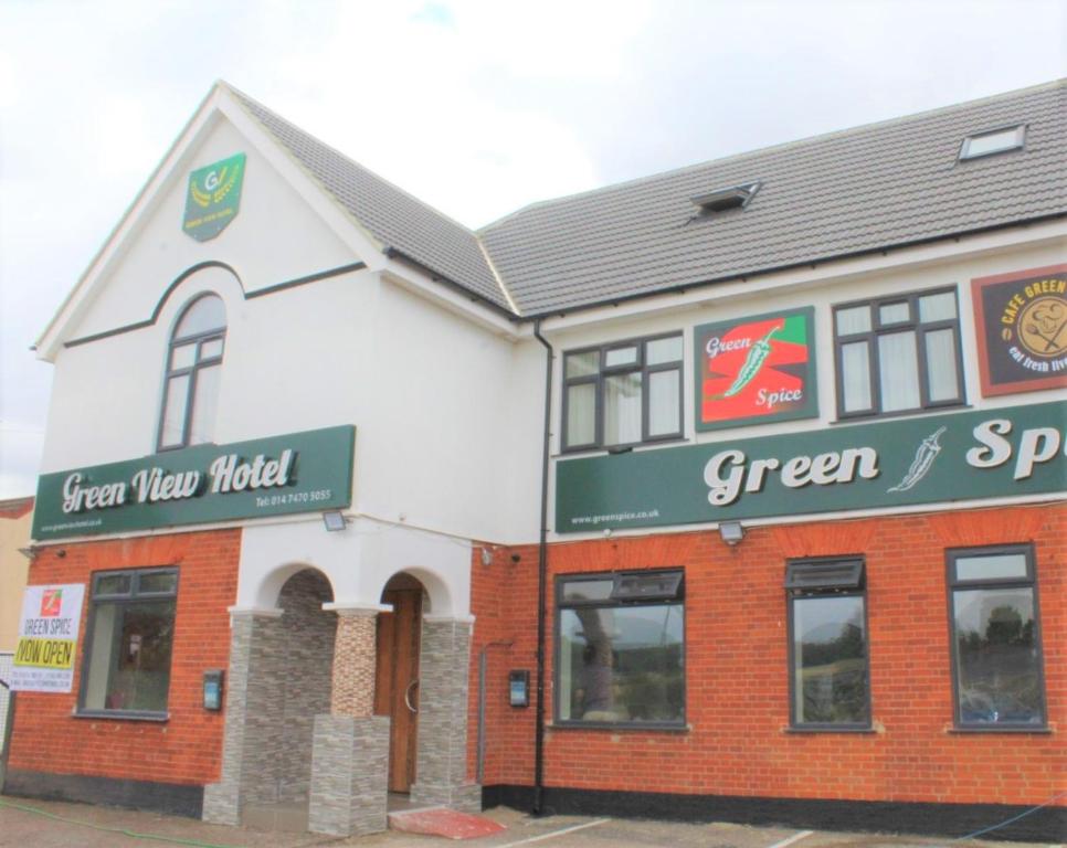 a white and red building with a green sign at Green View Hotel in Dartford