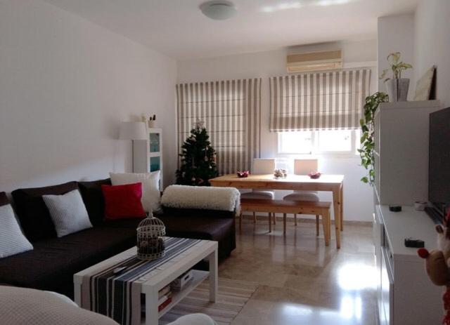 ein Wohnzimmer mit einem Sofa und einem Tisch in der Unterkunft Málaga Habitación en Apartamento Carlos Haya in Málaga