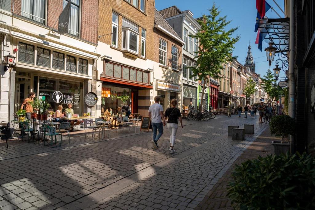 twee mensen lopen door een straat met gebouwen bij Lino City Hotel in Nijmegen