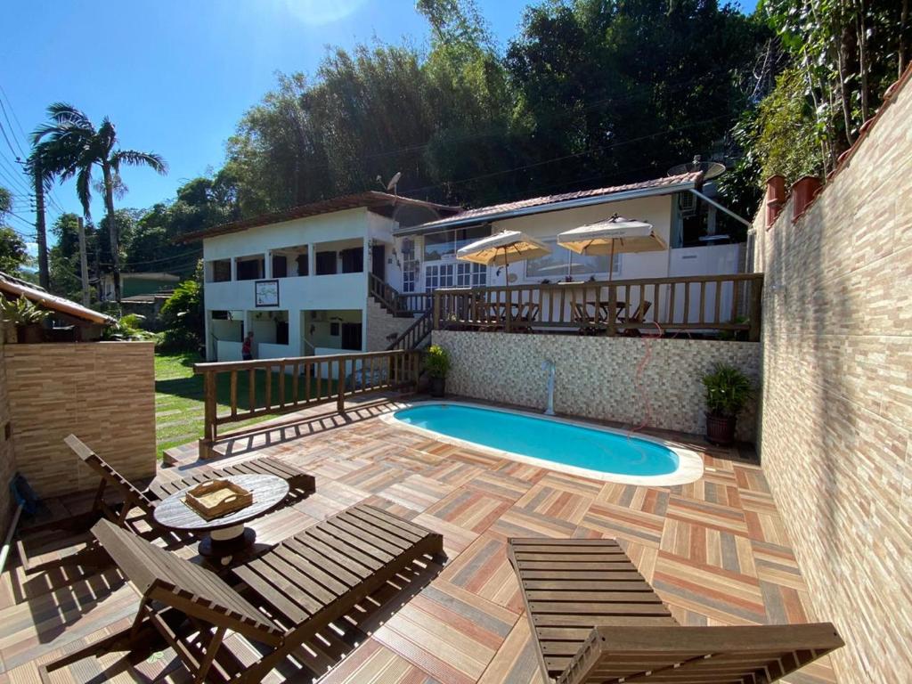 a patio with chairs and a pool and a building at Toca dos Pássaros in Boicucanga