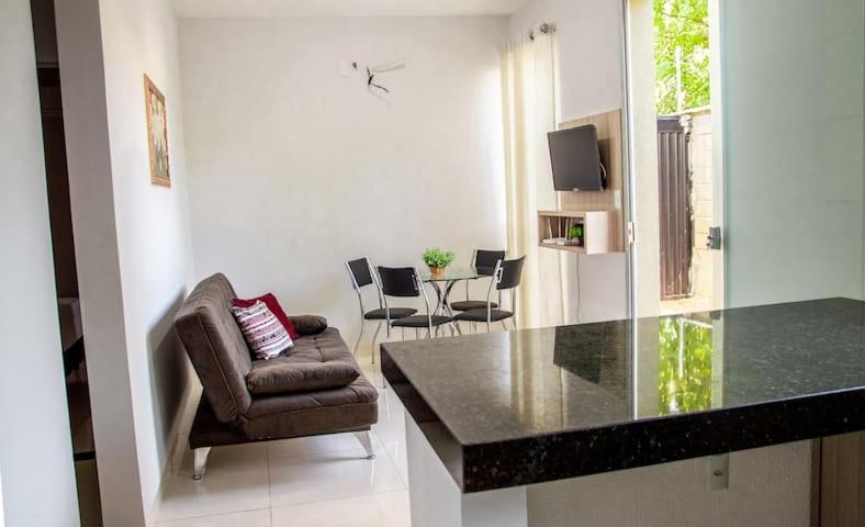 a living room with a counter and a chair and a table at Apartamento novo e completo no Centro de Palmas c/ internet in Palmas