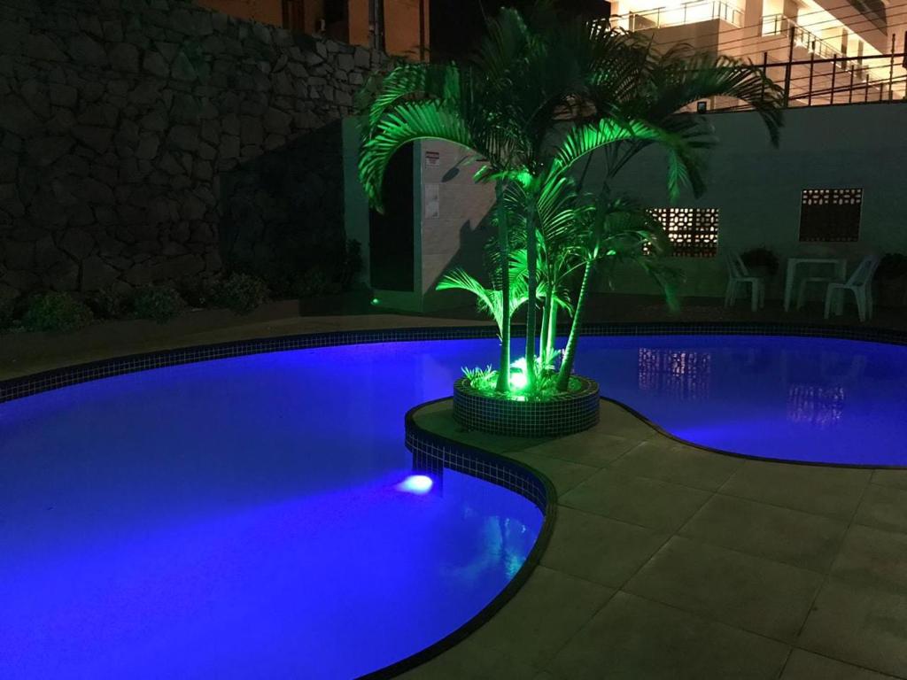 a pool with a palm tree and blue lights at Hotel Italia Beach in Fortaleza
