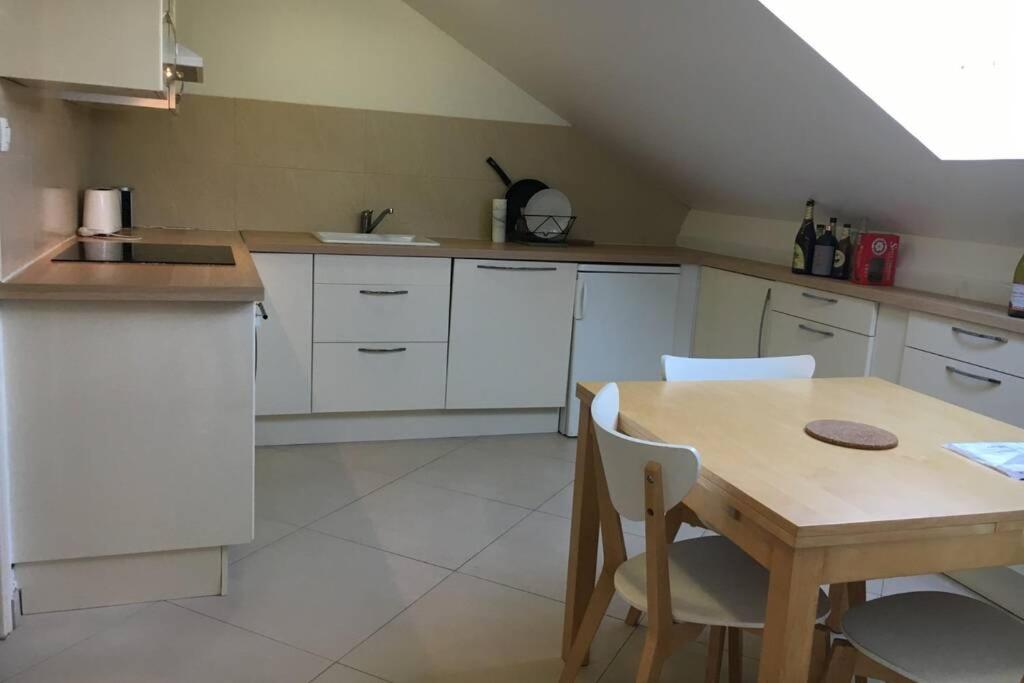 a kitchen with white cabinets and a table with chairs at Petit F3 sympa in Orsay