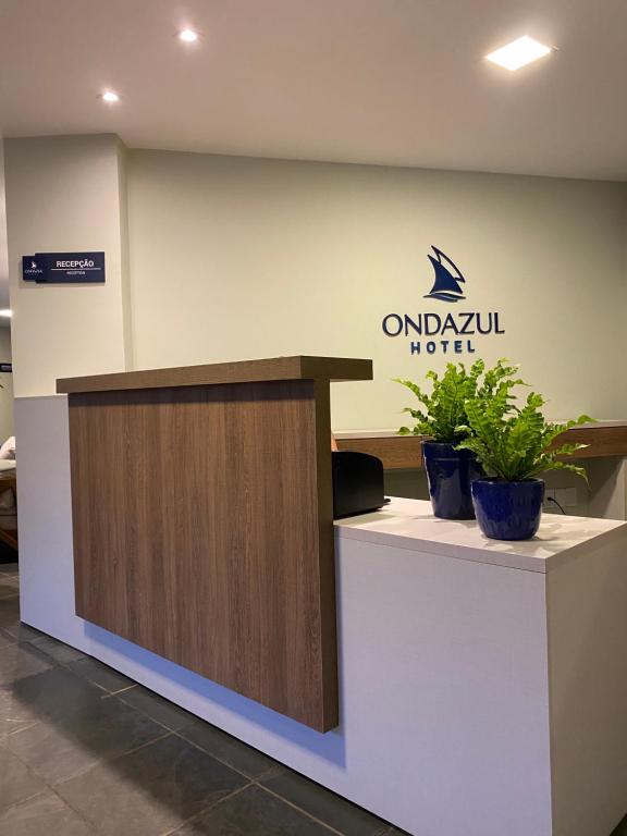 a reception desk in a hotel with two potted plants at Hotel Onda Azul in Valença