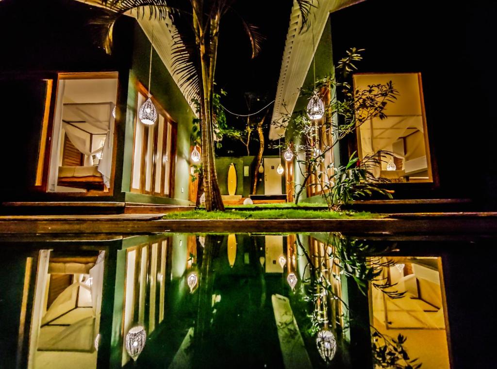 a house with a reflection in the water at night at Recanto de Sophie in Pipa