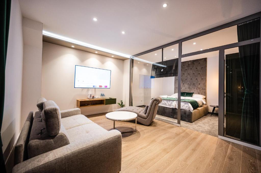 - un salon avec un canapé et un lit dans l'établissement DMS Apartments & Suites Sarajevo, à Vogošća