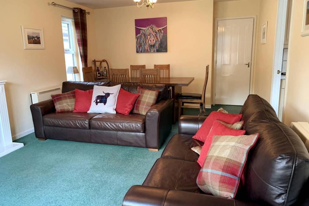 a living room with two leather couches and a table at Cairngorm Cottage in Aviemore