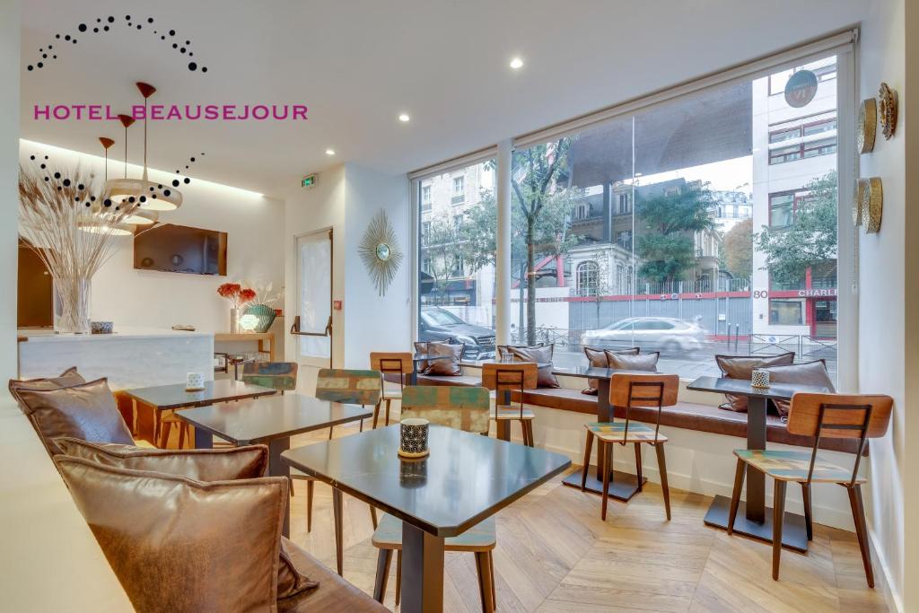 a restaurant with tables and chairs and a large window at Hotel Beausejour in Paris
