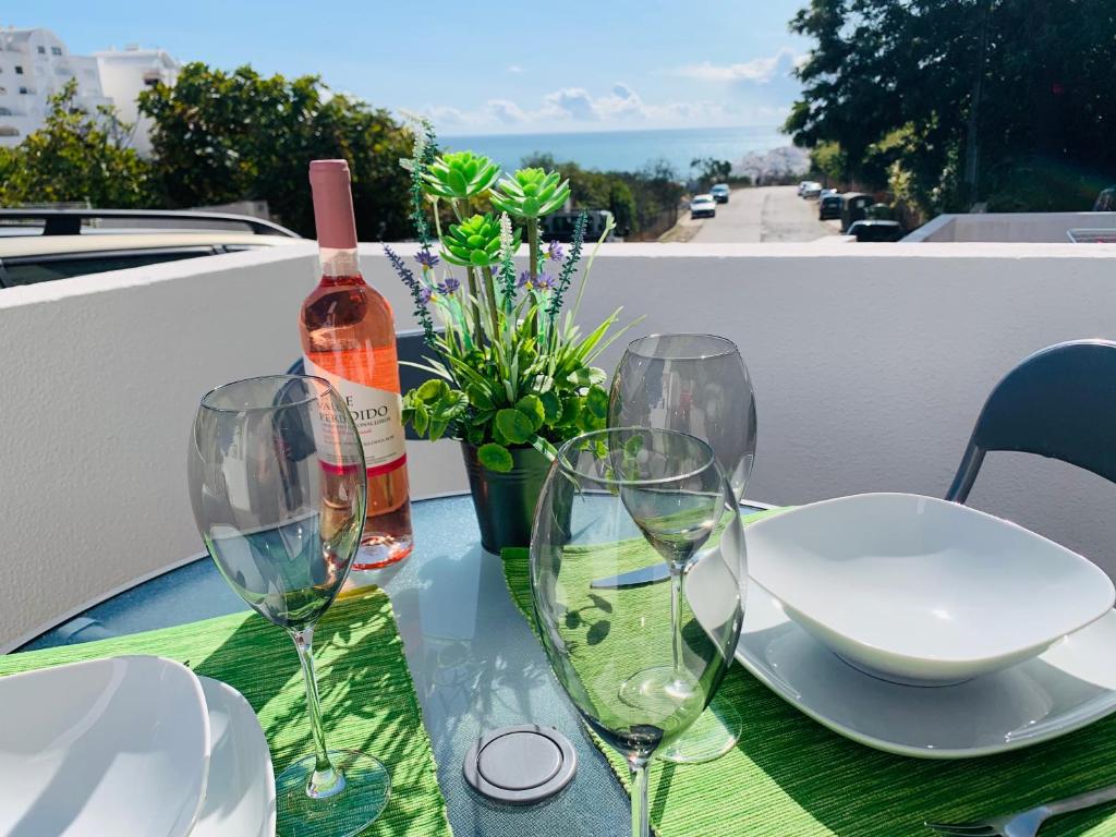 einen Tisch mit Gläsern und eine Flasche Wein in der Unterkunft COSY MODERN HOUSE - CENTER ALBUFEIRA - OLD TOWN in Albufeira