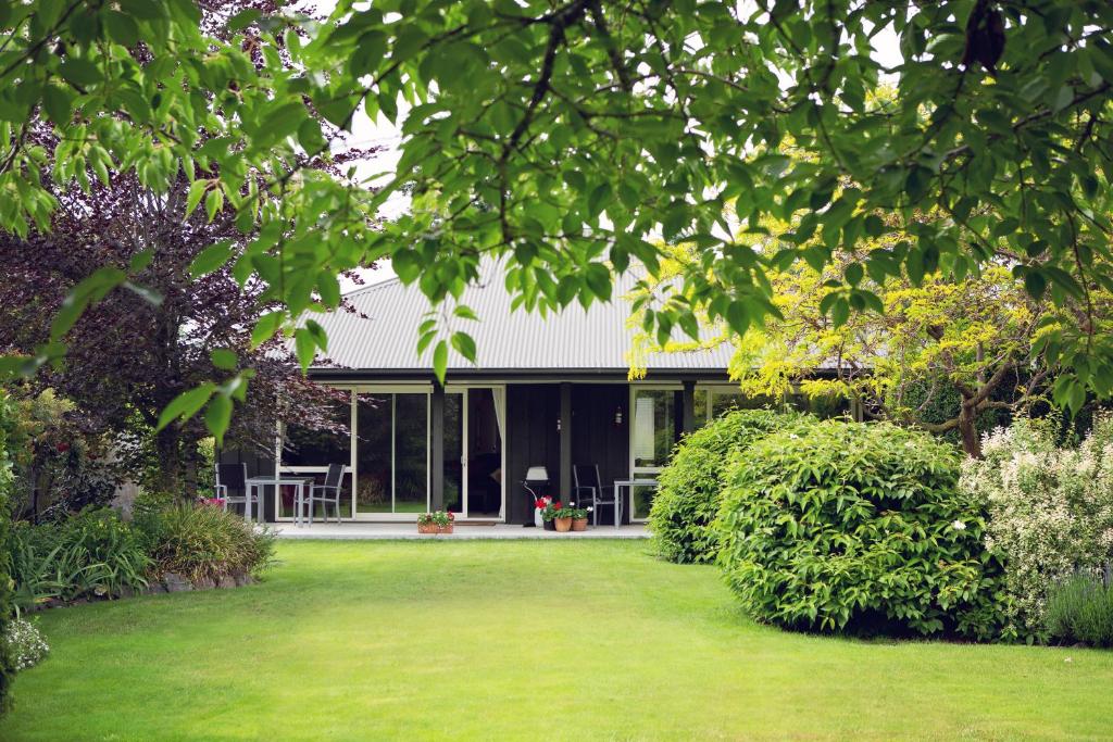 dom z zielonym trawnikiem przed nim w obiekcie Marchmont Gardens w mieście Hanmer Springs
