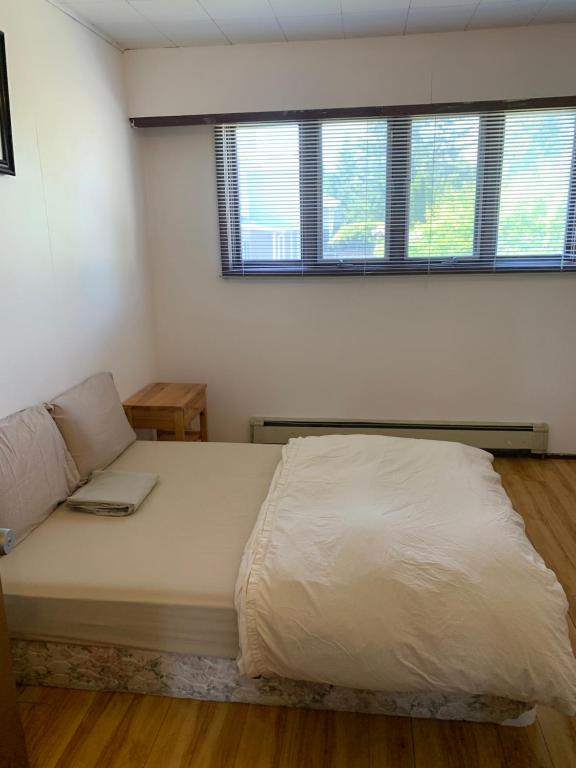 a large bed in a room with two windows at Vancouver Backpacker House in Burnaby