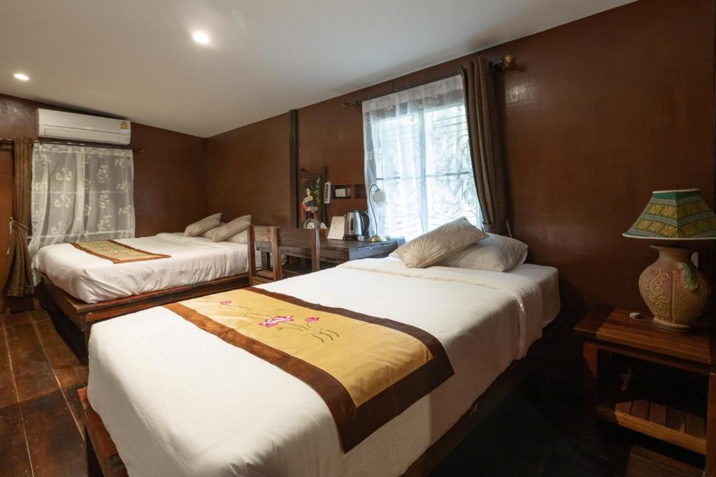 1 dormitorio con 2 camas y ventana en Reuan Vilawan en Ratchaburi