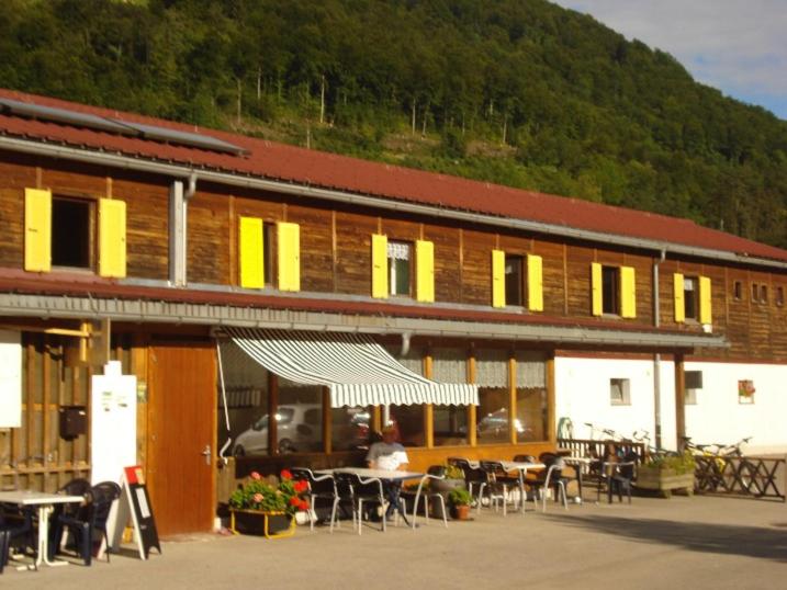 un edificio con tavoli e sedie di fronte ad esso di Hostel Le Chandelier a Saint-Ursanne