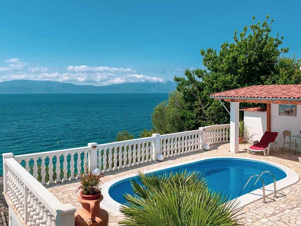 a swimming pool next to a white fence and the ocean at Villa Marritanja in Podaca